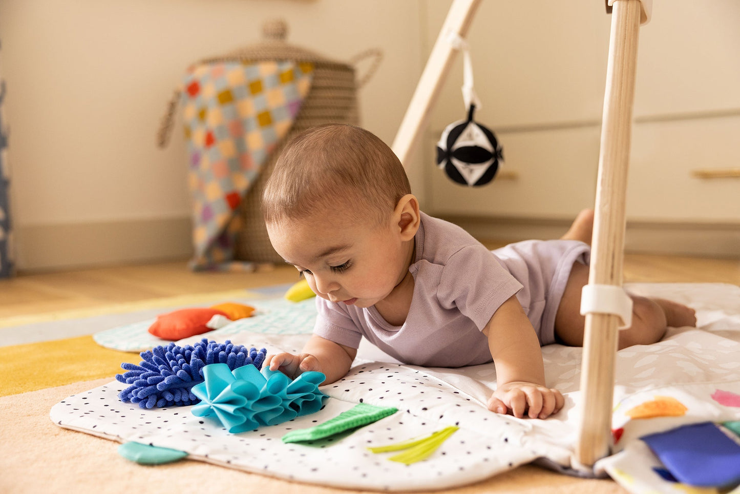 Montessori - aligned play gym for babies with sensory toys - The Nurturing Nook