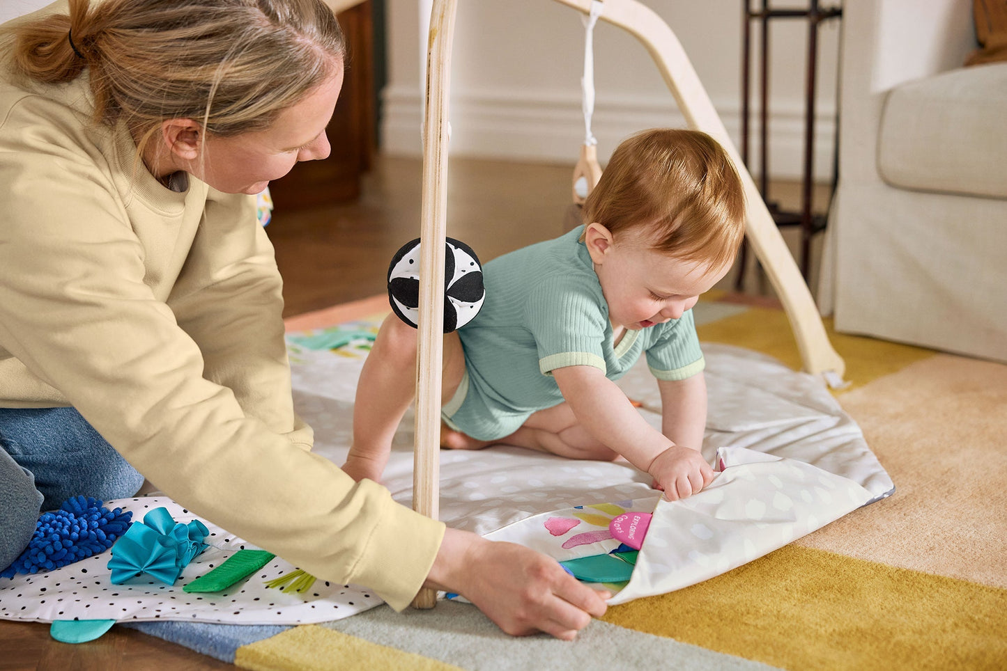Montessori - aligned play gym for babies with sensory toys - The Nurturing Nook
