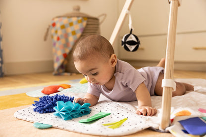 Montessori - aligned play gym for babies with sensory toys - The Nurturing Nook